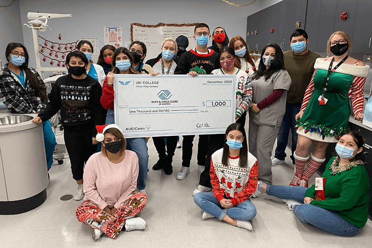 Students at UEI College in Chula Vista made donation after winning a social media contest - UEI College UEI college students holding large check