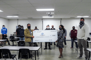 UEI college student holding large check