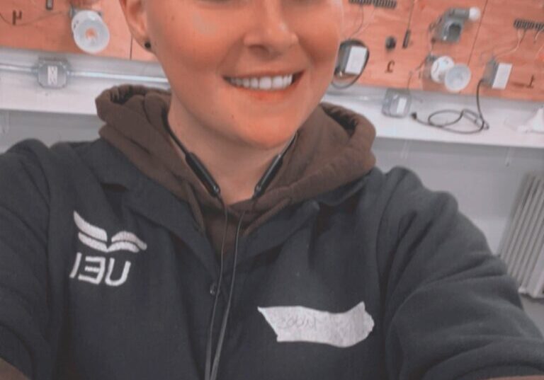 woman in a blue UEI uniform standing in the HVAC lab