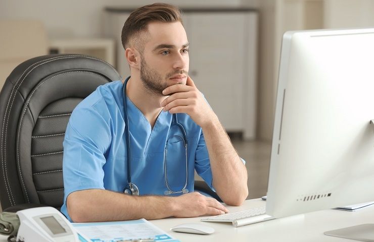 male medical assistant looking at computer monitor